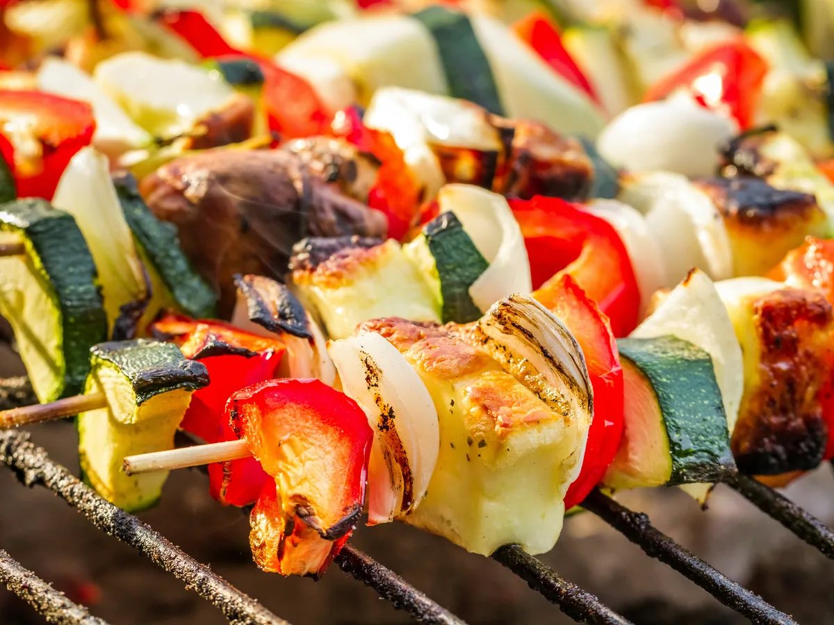 Vegetable skewers grilling over hot coals at the table barbecue